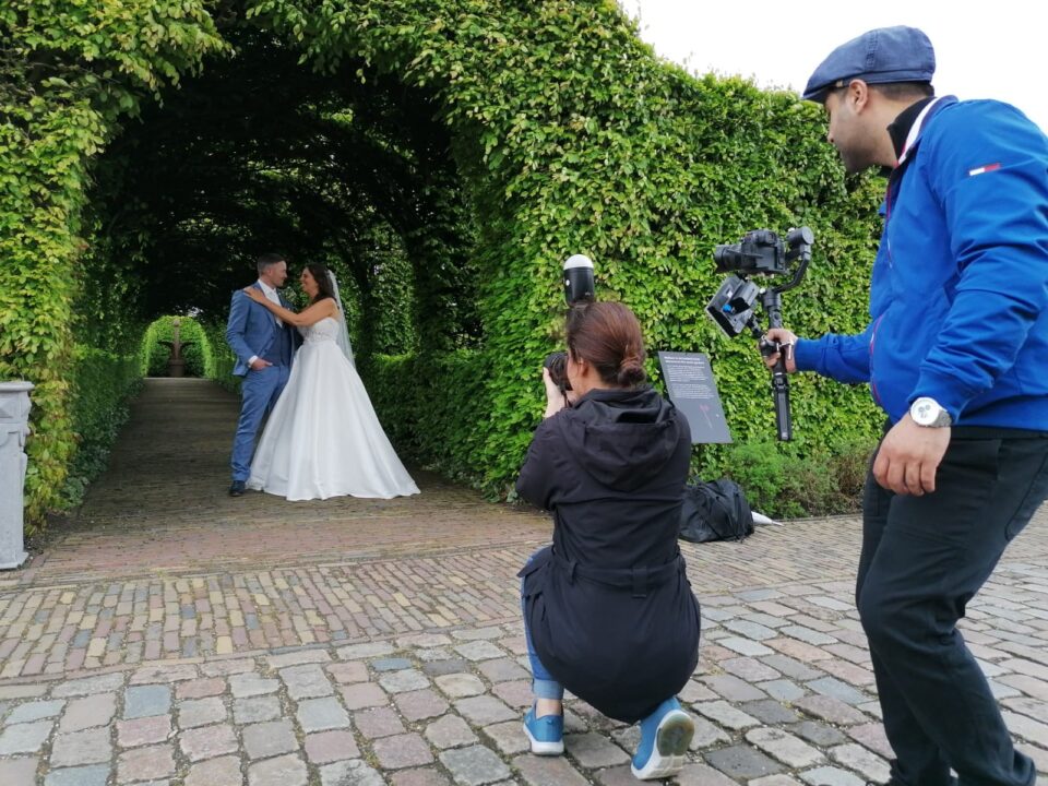 Een bruiloft op het Muiderslot. Het bruidspaar wordt gefotografeerd onder de beukenloofgang.