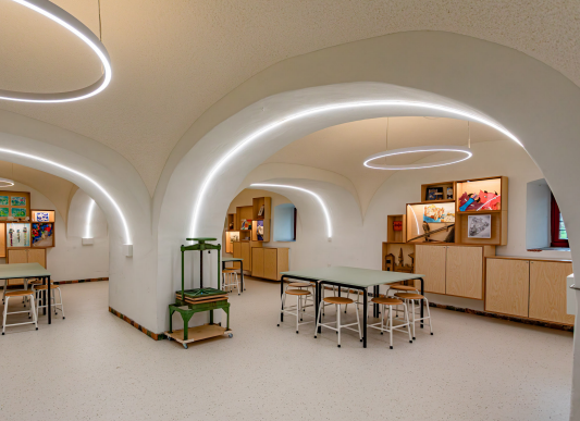 Het Kasteelatelier van het Muiderslot. In de ruimte is de historische structuur van het kasteel zichtbaar, met moderne, ringvormige verlichting en lichtstrips die de bogen volgen.