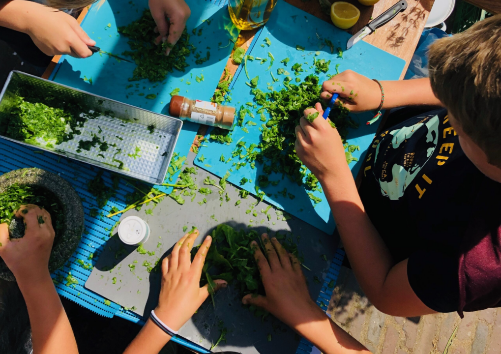 Kinderen zijn kruiden aan het snijden tijdens de kinderkookclub in het Muiderslot.