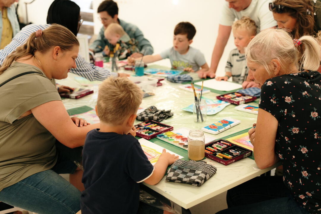In het Kasteelatelier zijn kinderen aan het schilderen met waterverf. Er staan kwasten op tafel.