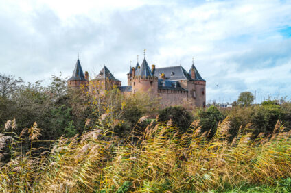 Het is herfst, licht bewolkt en het waait. Het Muiderslot staat op de achtergrond.
