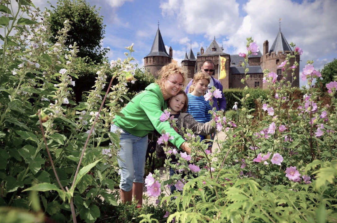 Een gezin staat in de tuin van het Muiderslot en bekijkt de bloeiende bloemen.