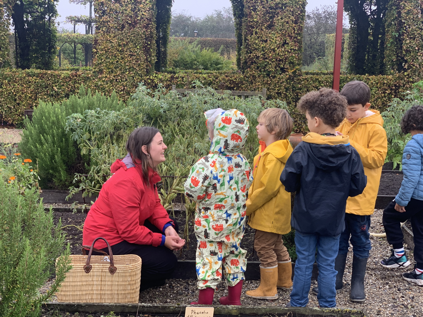 Kleine kinderen staan in de tuin van het Muiderslot met een rondleider.