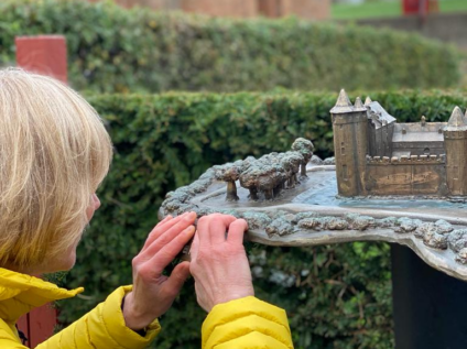 Iemand is een beeld van het Muiderslot aan het voelen, tijdens de workshop botanisch tekenen.