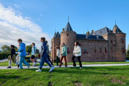 Een groep kinderen loopt buiten. Op de achtergrond is het kasteel te zien.