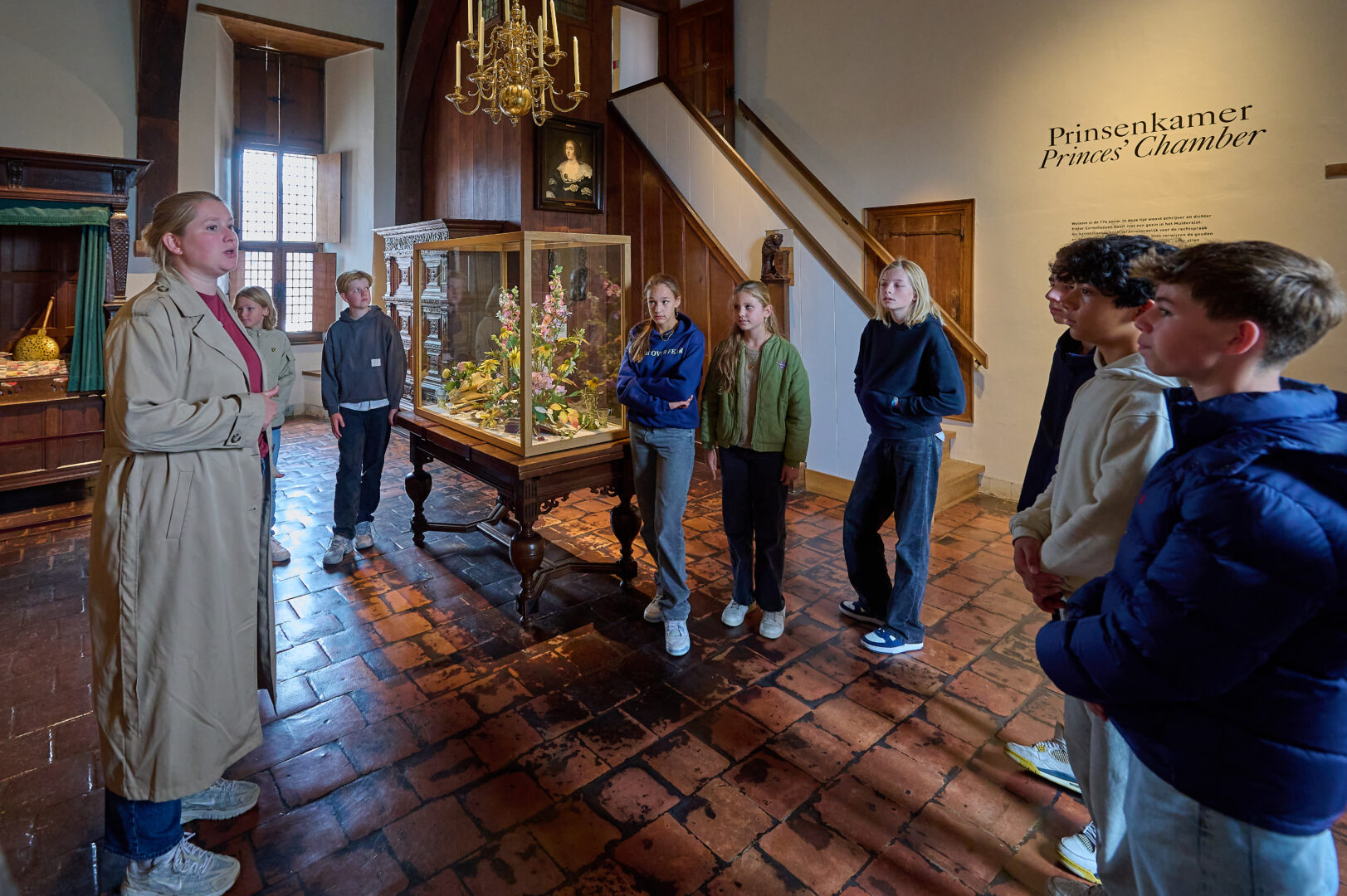 Middelbare scholieren staan in het Muiderslot en luisteren naar een rondleider.