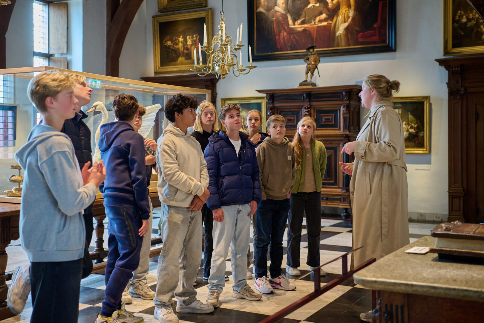 Een groep kinderen wordt rondgeleid in de Ridderzaal van het Muiderslot. Ze luisteren aandachtig naar de museumdocent.
