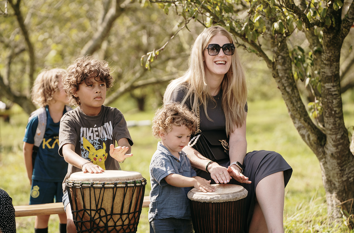 Moeder met jonge kinderen spelen samen djembe.