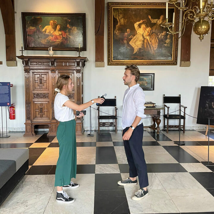 Podcastmaker Roos interviewt een gast op zaal in het kasteel.