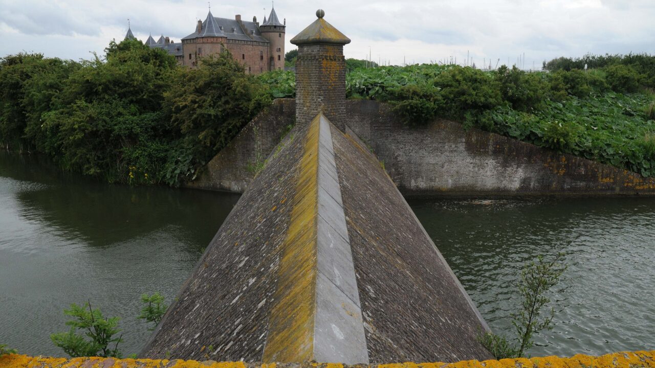 Een stenen beer met Muiderslot op de achtergond. Het is bewolkt.