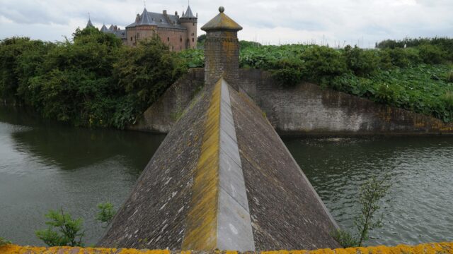 Een stenen beer met Muiderslot op de achtergond. Het is bewolkt.