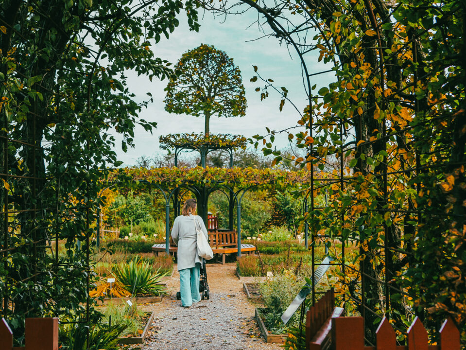 Vrouw met kind wandelen door de tuinen van het Muiderslot vol herfstkleuren.