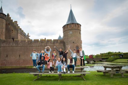 Kinderen staan op een picknicktafel voor het Muiderslot, in de zomer van 2020. Kinderen tussen 8 en 12 jaar oud deden mee aan een zomerschool samen met Fawaka Ondernemersschool.