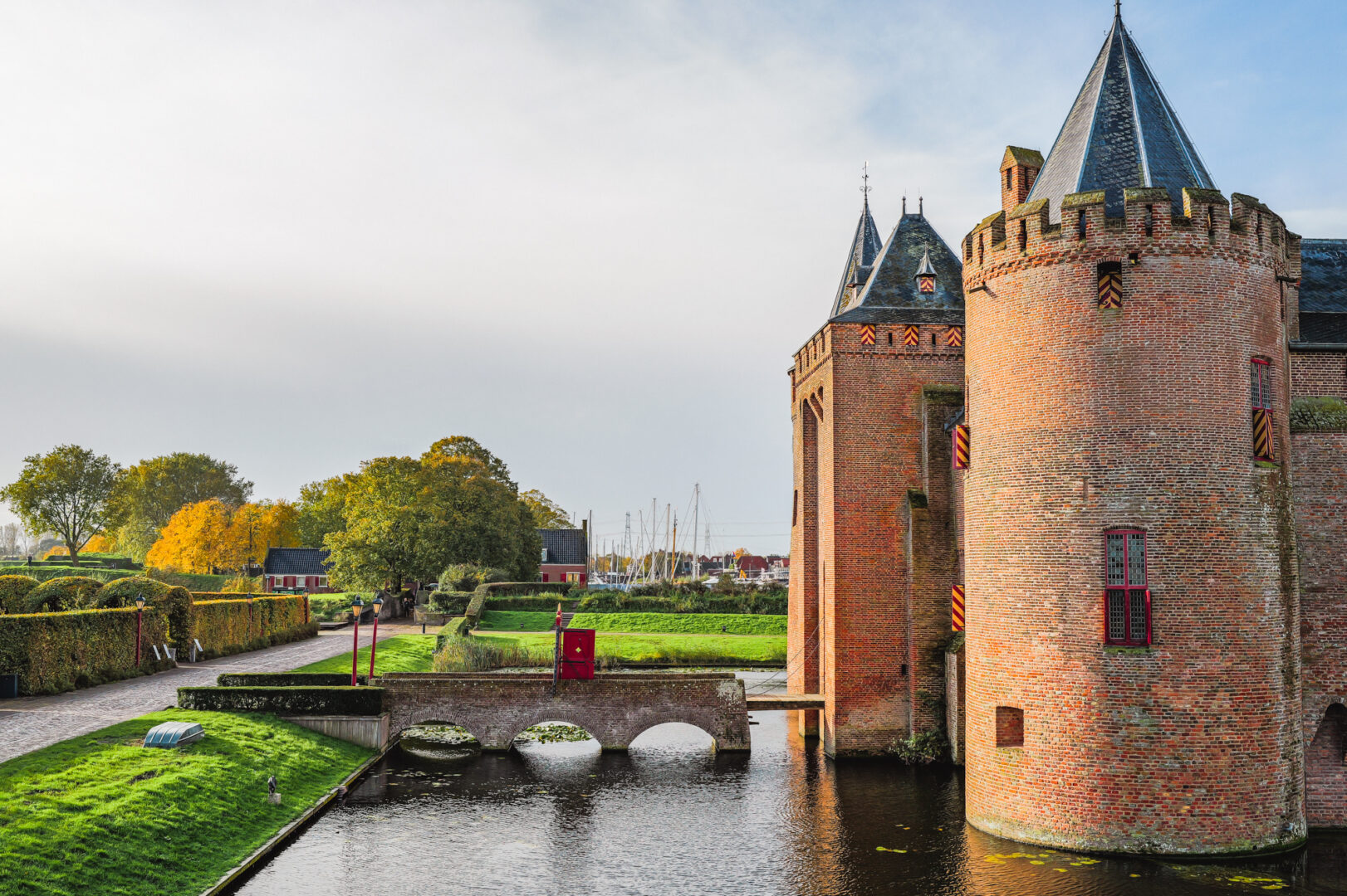 De zon schijnt. De rode poort van het Muiderslot staat open om gasten te ontvangen.