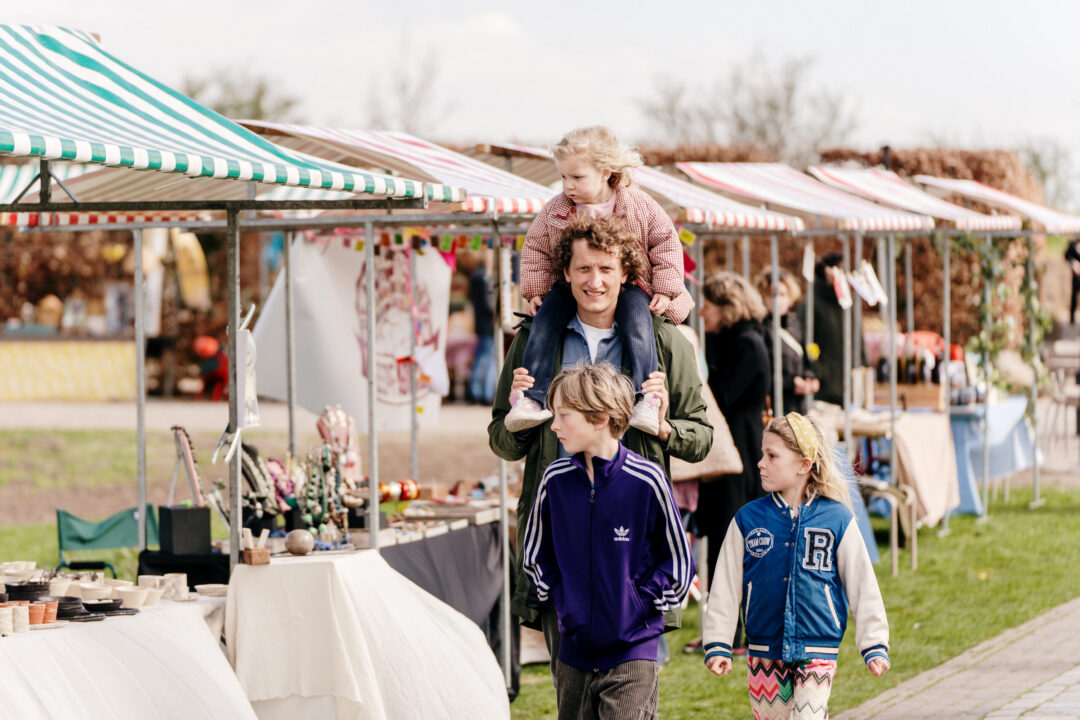 Het is lente. Een gezin is aan het rondlopen op de kasteelmarkt op het Muiderslot.