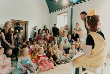 Een groep kinderen kijkt zittend op de grond naar een theatervoorstelling.