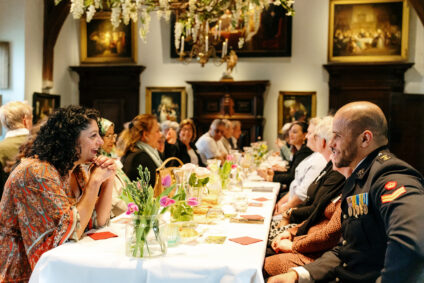 Het vrijheidsdiner van 2022 vond plaats in de Ridderzaal van het kasteel. De gasten zijn met elkaar aan het praten, en er staan roze tulpen op tafel.