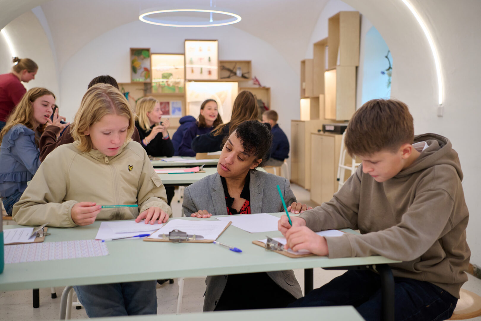 Klas aan het schrijven in het kasteelatelier onder leiding van een volwassene
