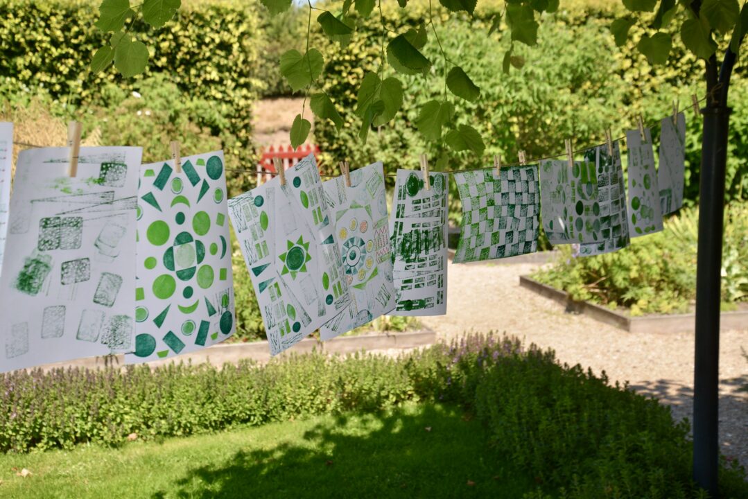 Getekende en gestempelde kunstwerken hangen aan een waslijn in de tuin van het Muiderslot.