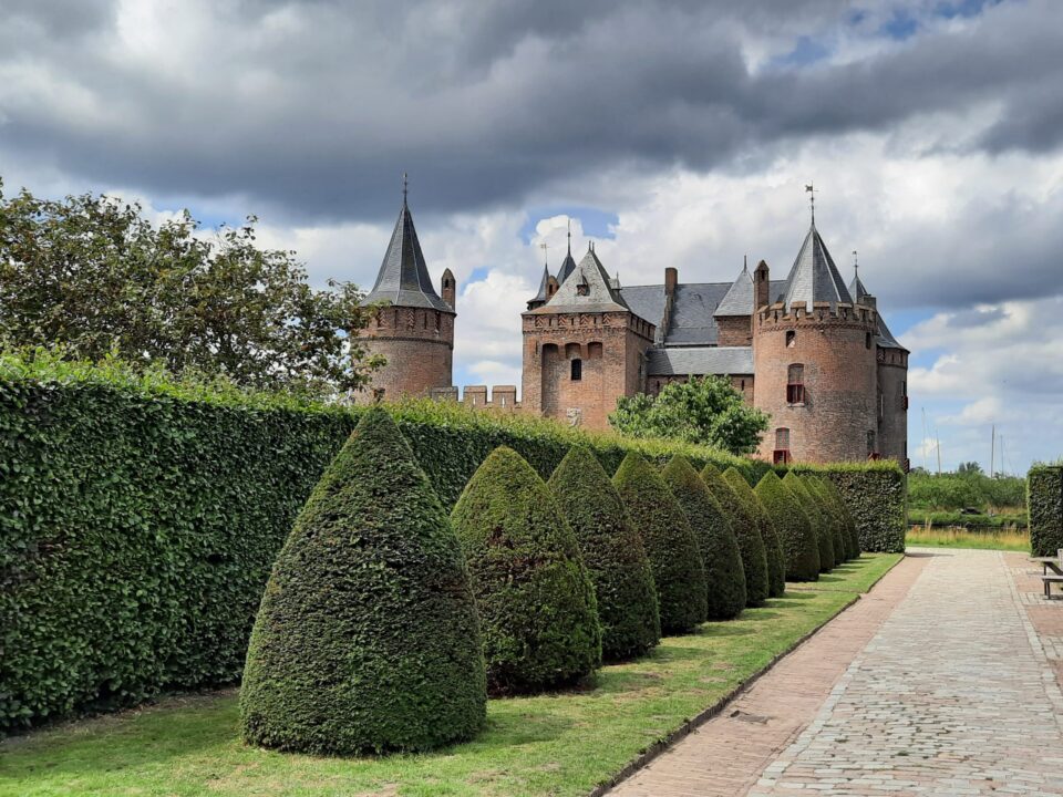 Muiderslot gezien vanuit de tuin in het zonlicht mar met donkere wolken.