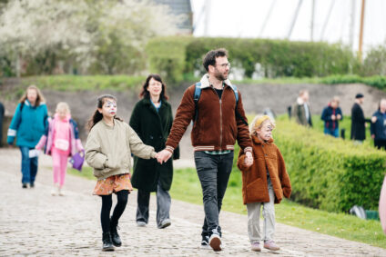 Gezin met kinderen loopt in de tuinen van het Muiderslot.