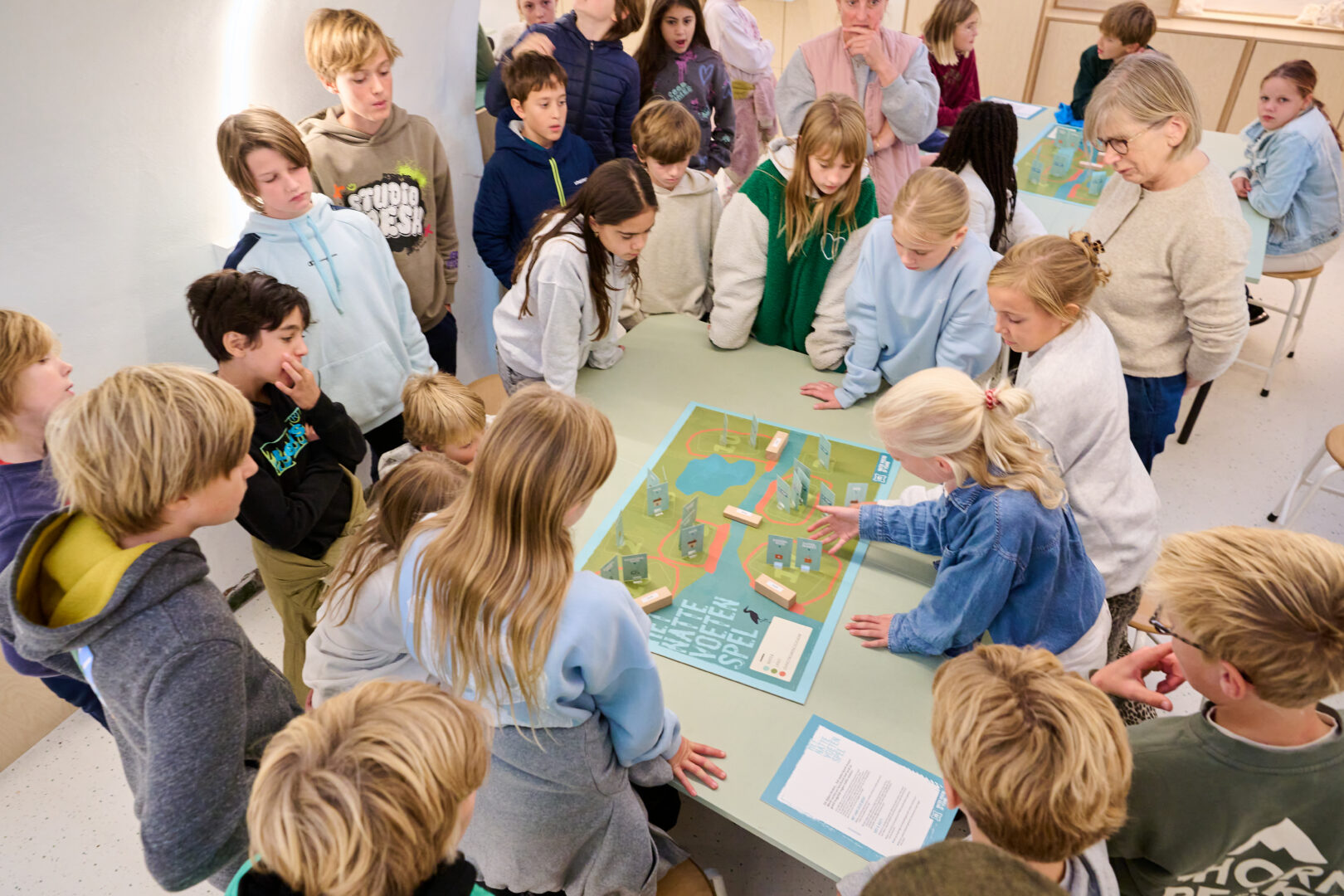 Een groep leerlingen staat rond een tafel en speelt een interactief spel in het kasteelatelier.