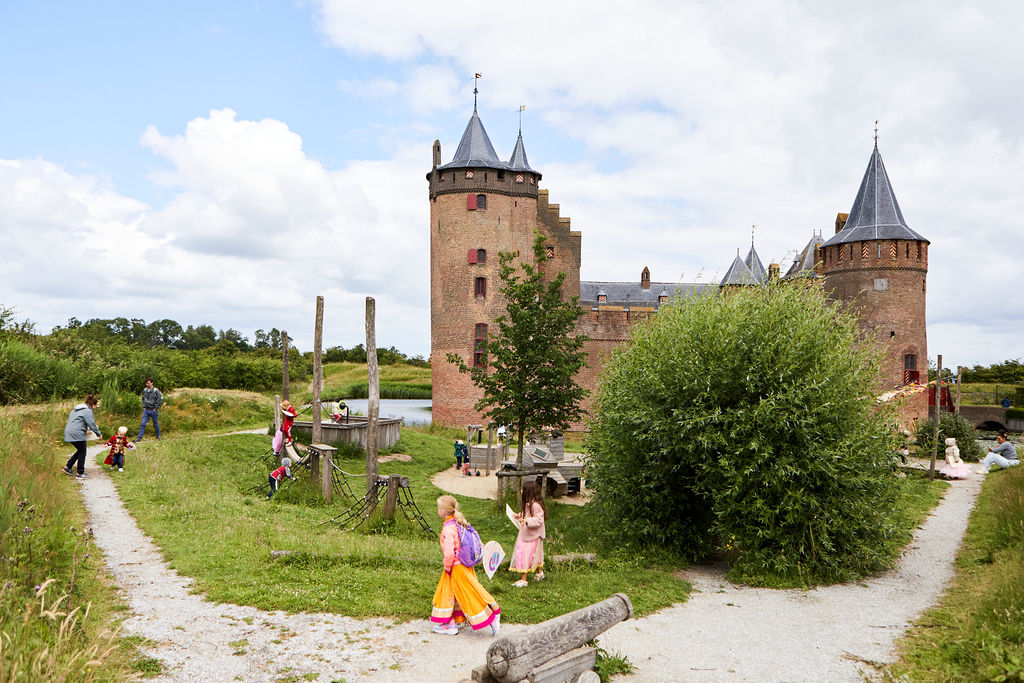 natuurspeeltuin met kinderen. Op achtergrond Muiderslot