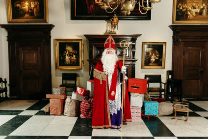 Sinterklaas in de ridderzaal met pakjes om hem heen